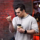 Henry Cavill holds a coffee while studying a tabletop gaming figure.